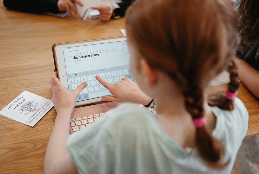 Girl seated at a table working on a laptop.