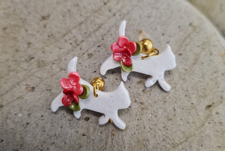 A pair of white cat-shaped polymer clay earrings.