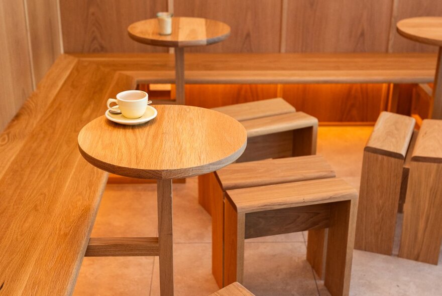 Small timber tables and stools with a single coffee cup.