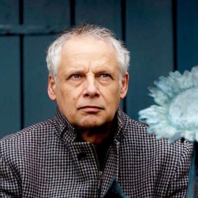 Dutch cellist Pieter Wispelwey, wearing a checked coat with blue sunflower against a blue door.