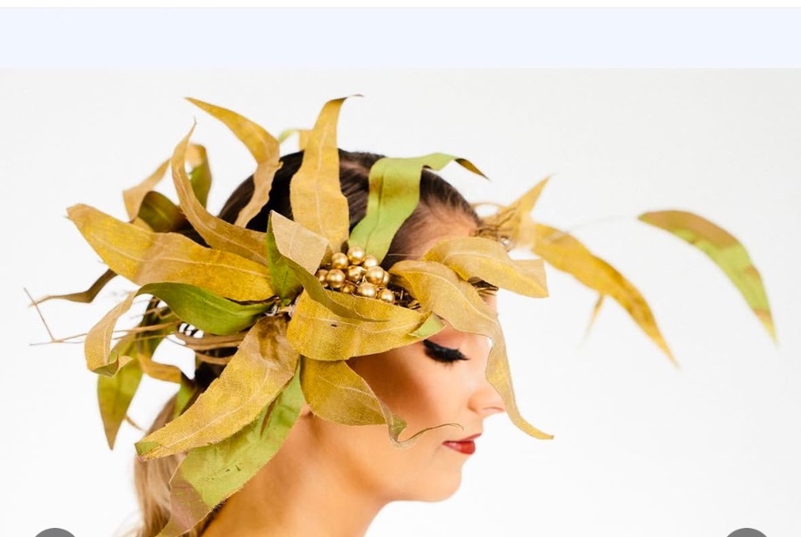 An elaborate headpiece comprised of hand painted silk pieces that resemble gum leaves, being worn by a fashion model.