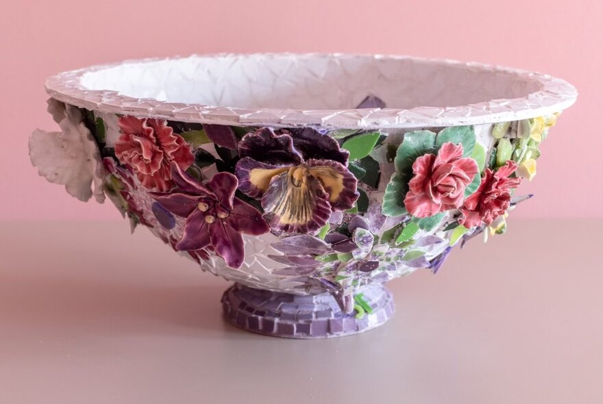 A mauve mosaic bowl covered in decorative flowers. 