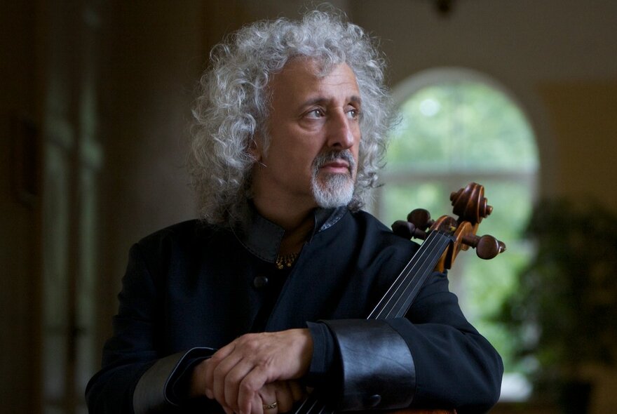 Classical musician with long curly white hair and beard, holding a stringed instrument.