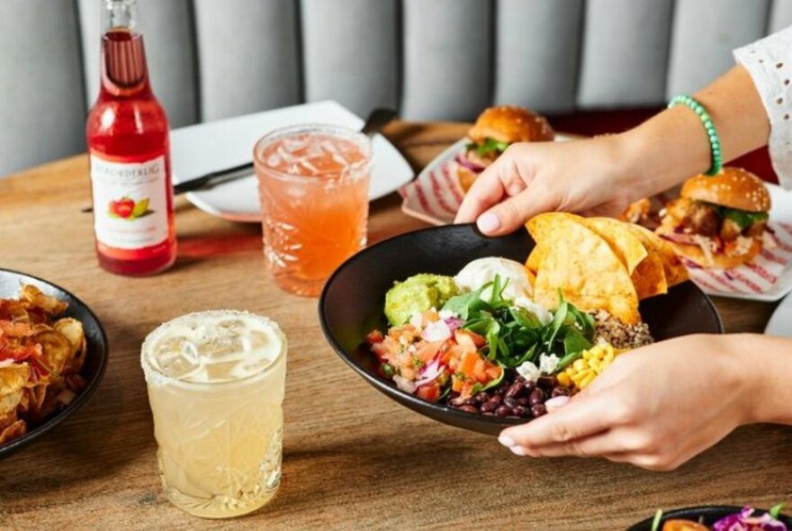 Plate of beans and tacos plus cocktails in tumblers.