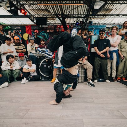 A person break dancing while others look on in a circle.