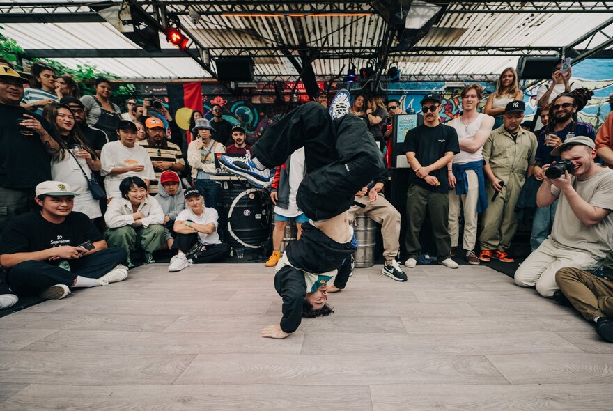 A person break dancing while others look on in a circle.