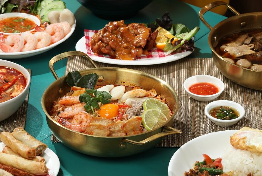 A selection of Thai dishes served on platters and plates on a restaurant table.