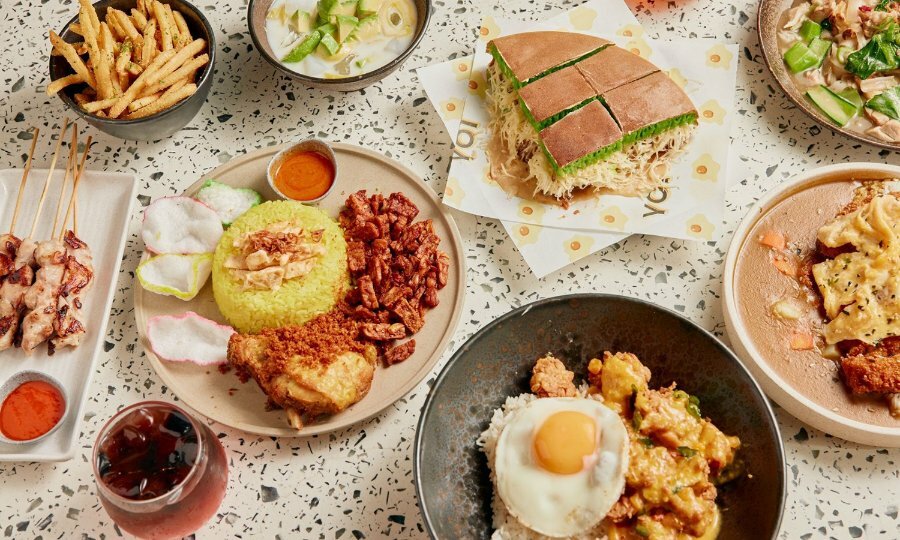 A table of Indonesian dishes including rich, fried chicken, egg, skewers and martabak.
