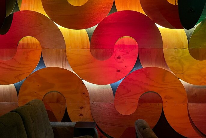 Soft lighting and sculptural details on the side wall of a cinema.