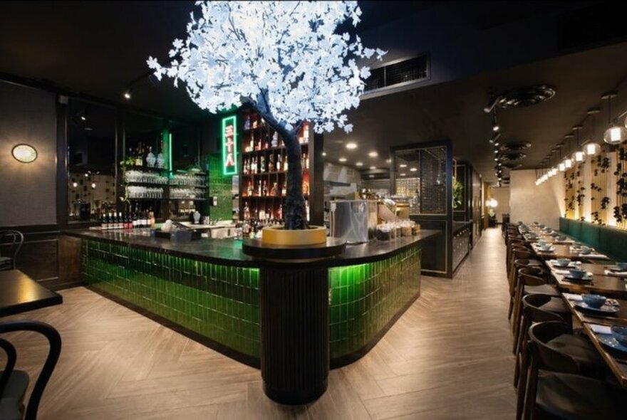 A restaurant bar with green tiles and a lit up tree