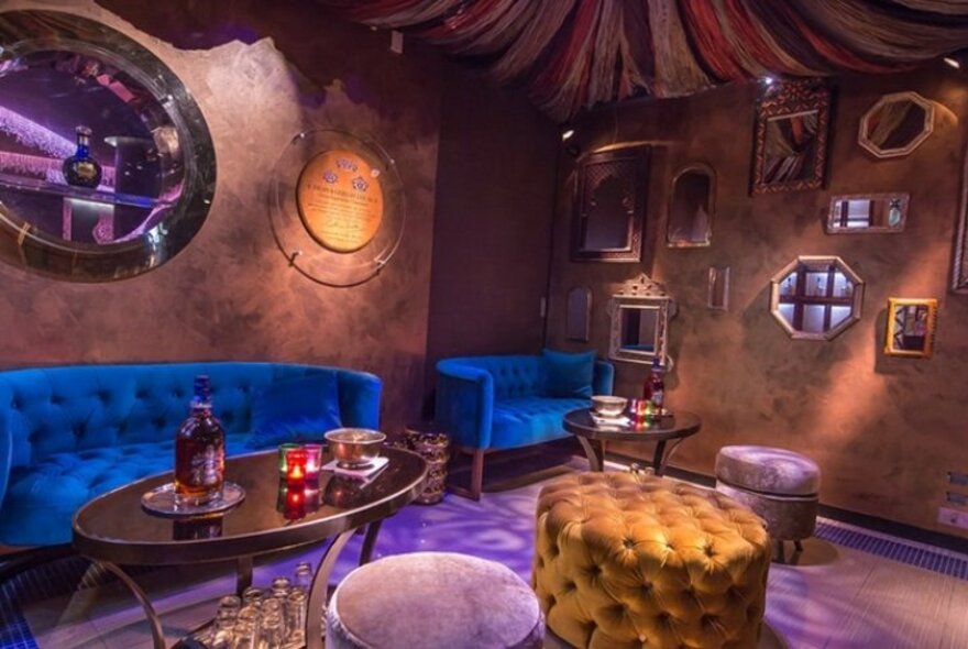 Opulent nightclub area with couches and mirrors on the walls.