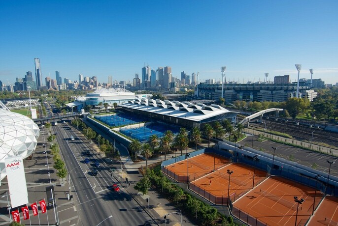 Several tennis courts and city buildings in the distance.