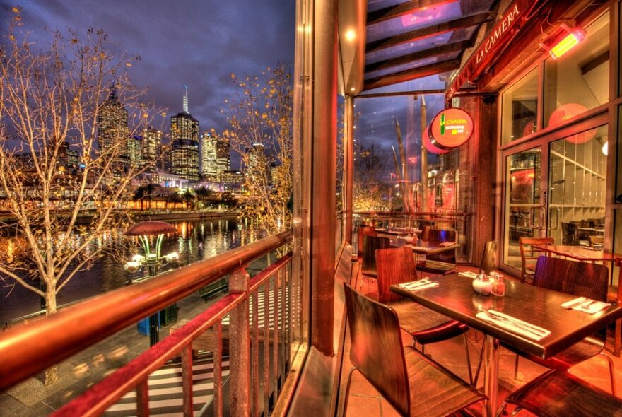 Restaurant outdoor dining area overlooking the Yarra River and trees.