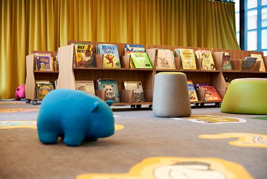 Children's space in a library with a wombat-shaped seat and shelves lined with picture books.