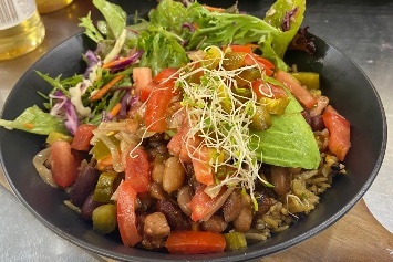 Salad bowl topped with alfalfa, shredded lettuce and chopped tomato.