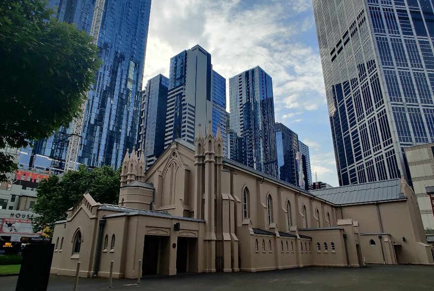Old church in central city location surrounded by towering office buildings.