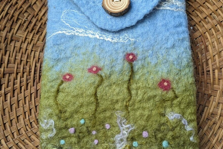 A small felted case with a botanical design and a button fastening.