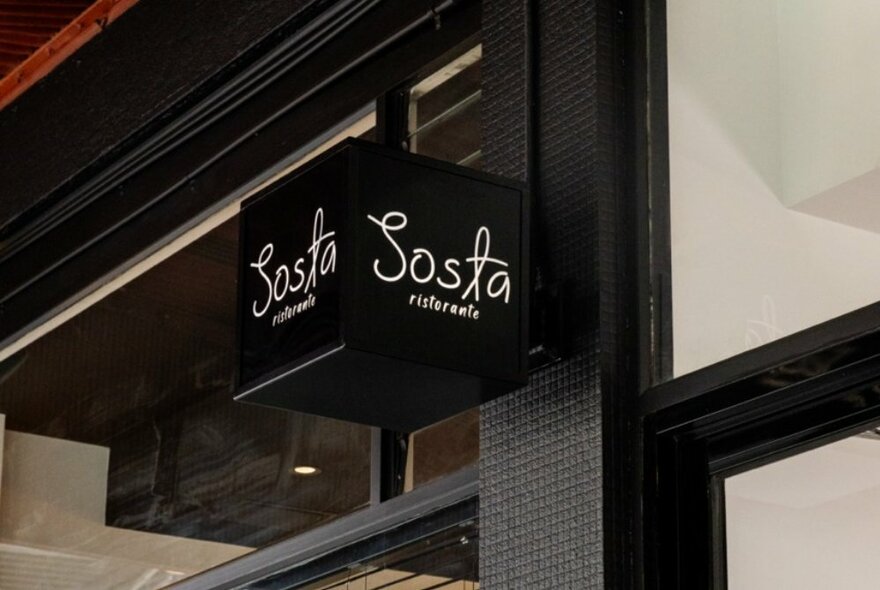 The exterior of Sosta Ristorante with a black cube sign.