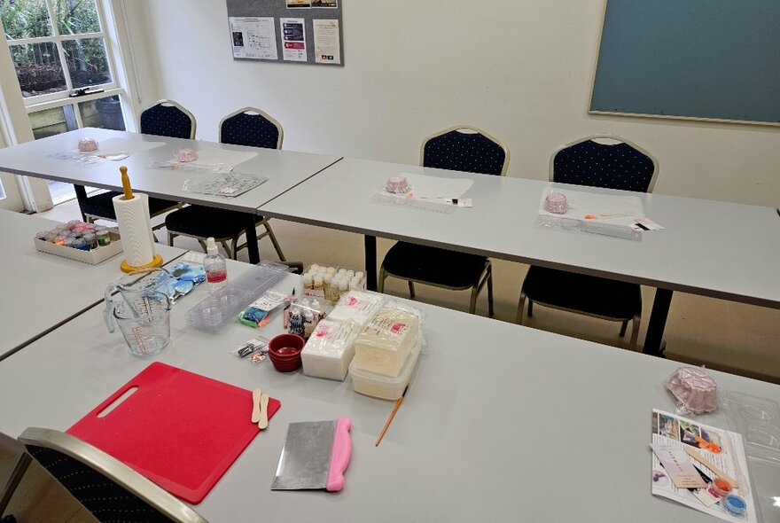 A room with chairs and tables, with equipment on the tables used to make soaps.