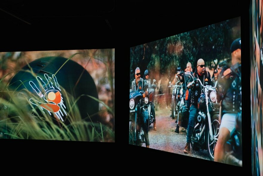 Two screens side by side, one showing an Aboriginal flag on a cut-out hand near a tunnel and the other showing an Indigenous motorcycle group.