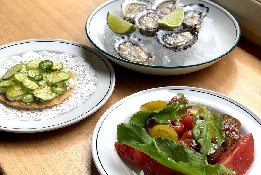 Fresh oysters with lime wedges, cucumber slices and green chilli and side salad. 