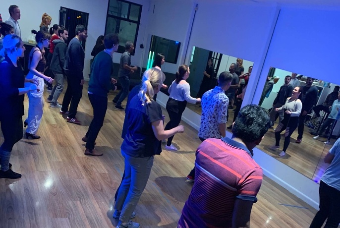 Lines of people facing a mirror learning how to salsa dance. 