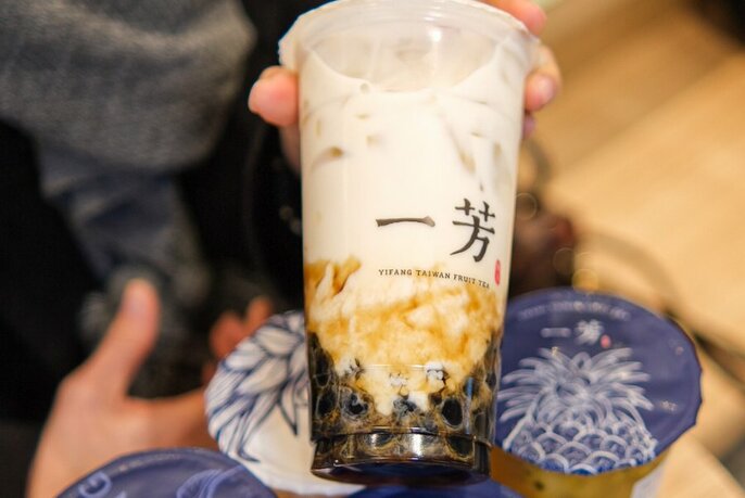 A tall sealed plastic cup of milky looking fruit tea.