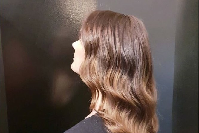 Side view of a woman with brown wavy hair. 
