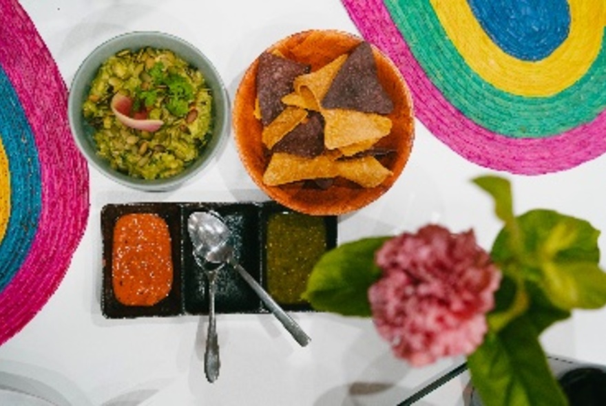 Bowls of Mexican food including chips and guacamole with dips.