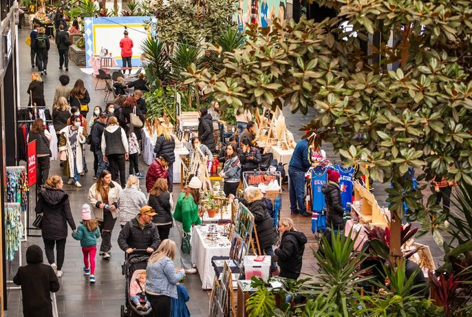 Overhead view of shoppers browsing indoor stalls with foliage.
