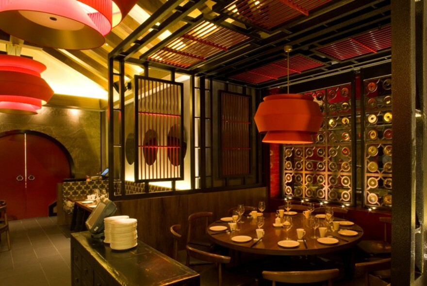 Private screened booth with large round table and large lantern overhead.