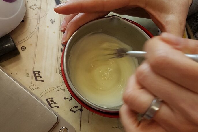 A hand whisking ingredients in a small metal bowl.