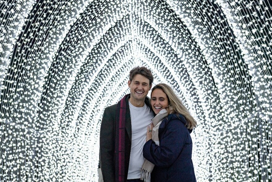A couple embracing in a glowing tunnel of lights.