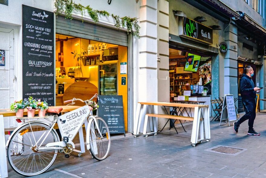 A tiny laneway cafe with a bicycle and plants outside.