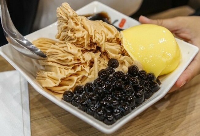 A white plate with shaved ice dessert in it