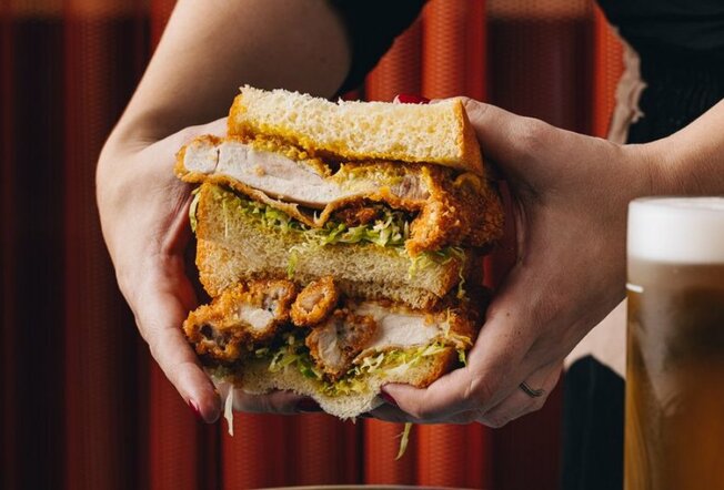 A person holding a fried chicken sandwich with two hands