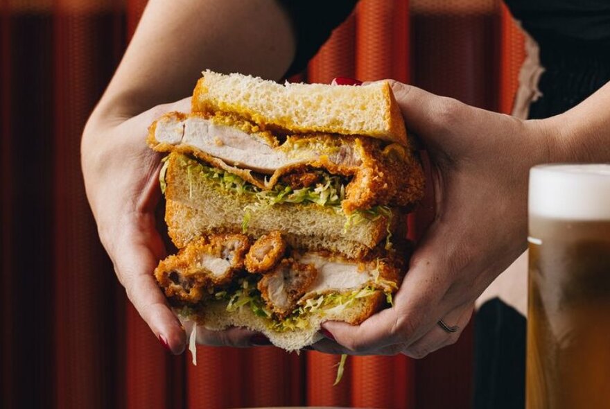 A person holding a fried chicken sandwich with two hands