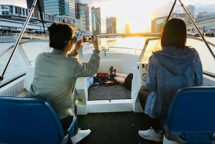 Three women enjoying the sunset on a fishing speed boat and taking a photo. 