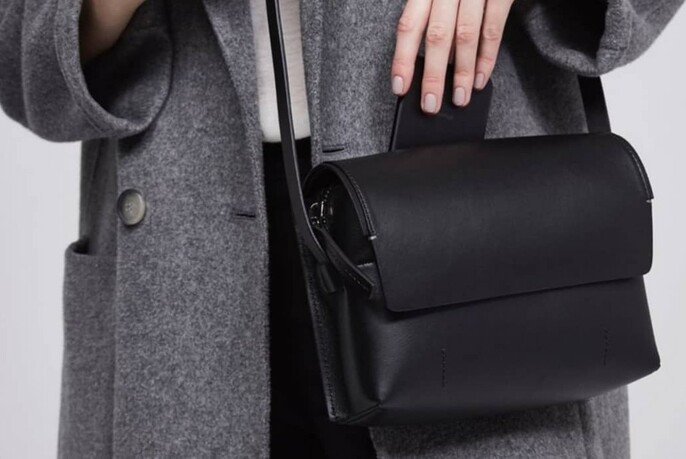 Model wearing a grey winter coat with a black shoulder bag.