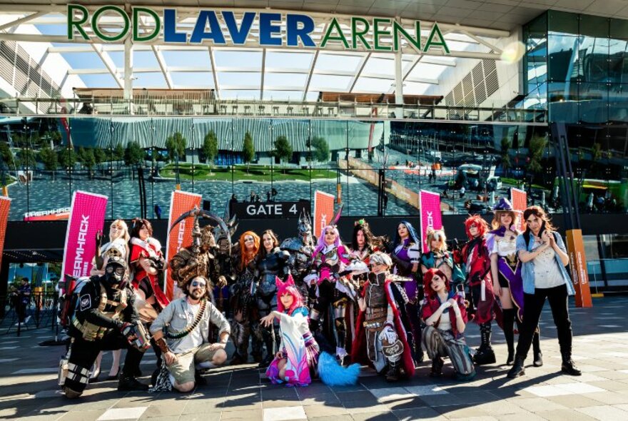 A group of people in cosplay with pink banners outside Rod Laver Arena.