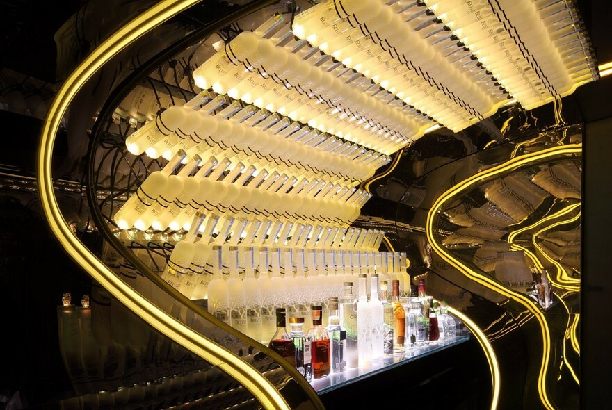 Bottles of alcohol in illuminated rows in a bar.