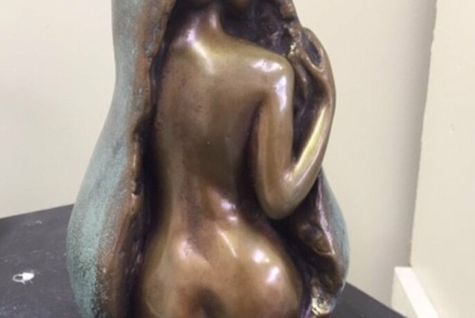 Detail of a metal sculpture, a naked female form emerging from a natural form.