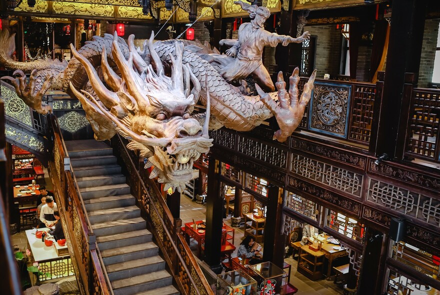 Giant Chinese dragon suspended over restaurant a staircase.