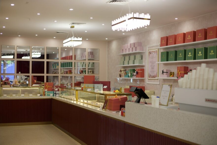 The tidy interior of a cake shop with a long counter.