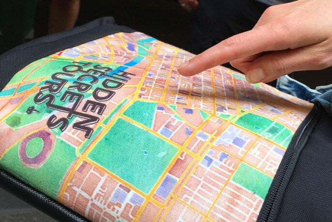 Person pointing to a Hidden Secrets Tour map.