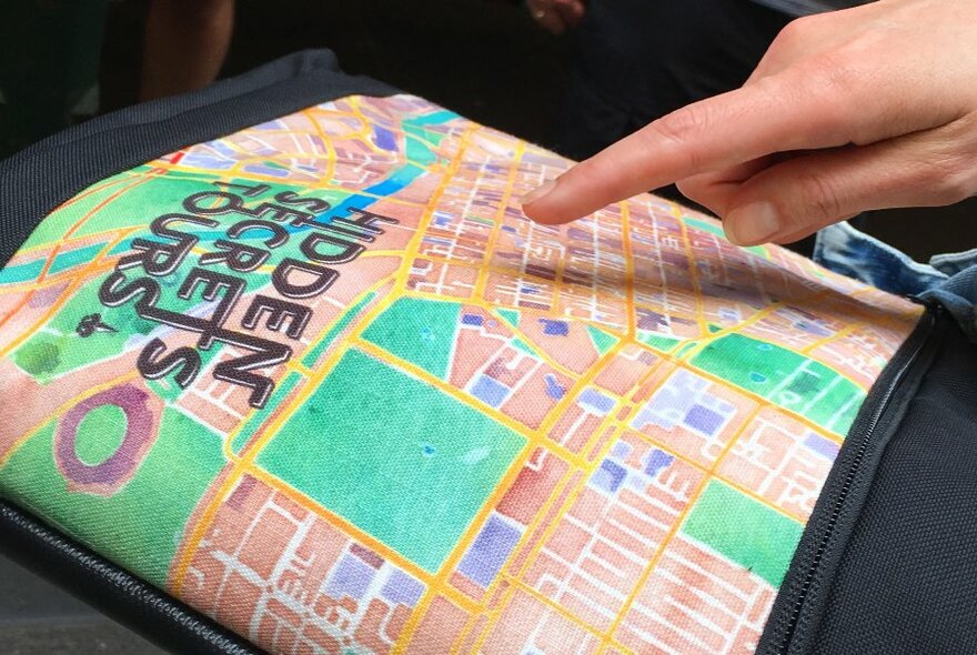 Person pointing to a Hidden Secrets Tour map.