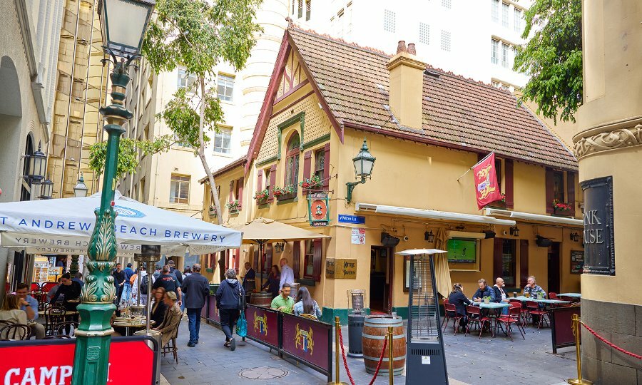 People dining in a laneway outside an old cottage-style city pub.
