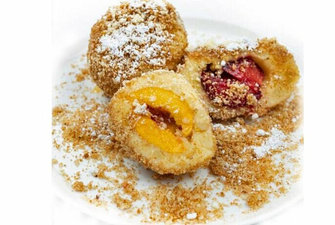 Apricots coated in biscuit crumbs and icing sugar.