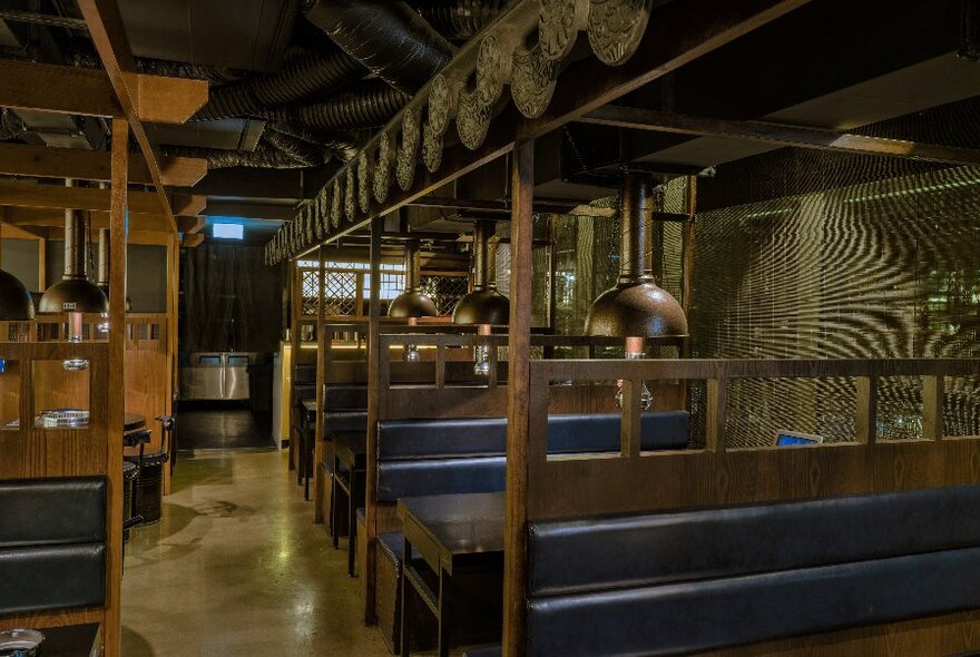 Wooden restaurant interior with booths with blue seats to right hand side.