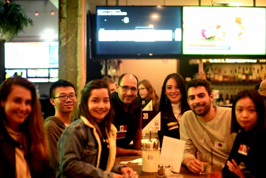 Group of people smiling and seated around a table in a pub.